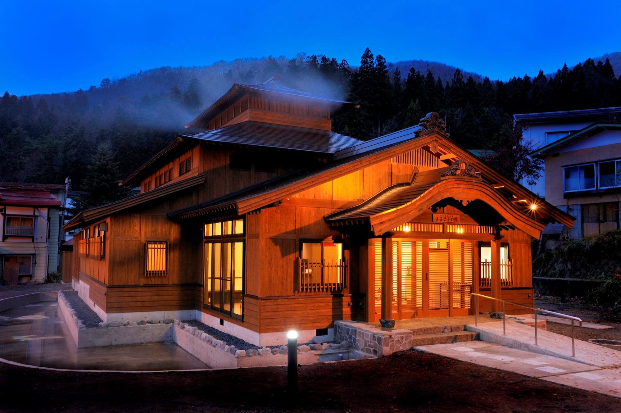 Traditional Japanese bathhouse glowing amber at night with mountain mist