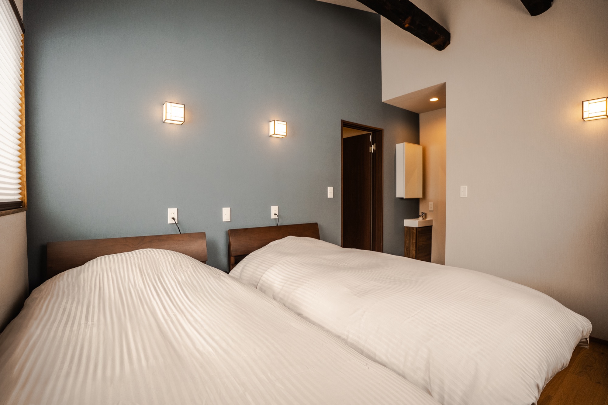 Bedroom with beautiful slate-blue accent wall and warm Japanese lantern sconces